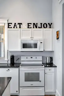 a kitchen with white appliances and a sign that reads eat entropy at The Harlequin - 20 Summer Village in Cherry Valley