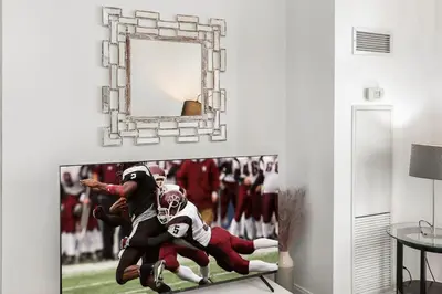 a tv with a football picture on a wall at Luxurious 2BR 2BATH Condo Steps from Square One in Mississauga