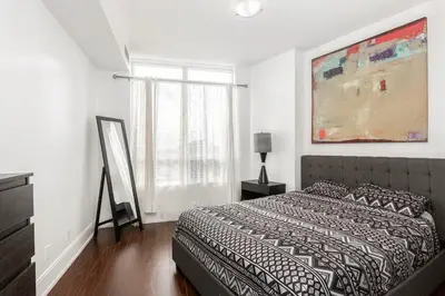 a bedroom with a bed and a painting on the wall at Luxurious 2BR 2BATH Condo Steps from Square One in Mississauga