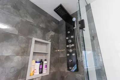 a shower in a bathroom with bottles on a shelf at An Ideal Home Away From Home in London