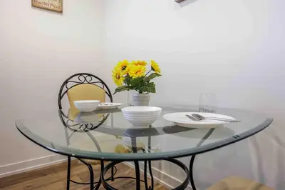 a glass table with two chairs and a vase with flowers at Cozy 2Bed Home 6 minutes to the FALLS! in Niagara Falls