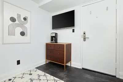 a room with a tv and a dresser and a door at La TUMU in Toronto