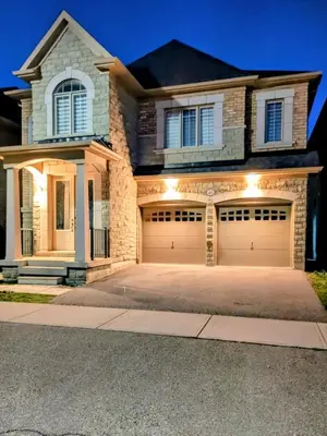 a house with two garage doors on a driveway at Kings Palace Basement in Brampton