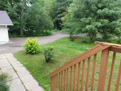 a yard with a wooden fence and a road at Amazing Lakefront cottage on Paradise Lake in Haliburton