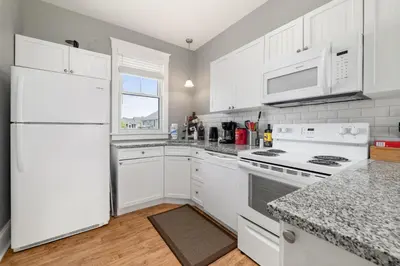 a white kitchen with white appliances and a window at The Osprey - 41 Butternut in Cherry Valley