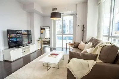 a living room with a couch and a tv at Luxury Condo with Pool, CN Tower View, Gym, Workspace in Toronto