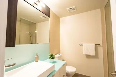 a bathroom with a sink and a toilet and a mirror at Luxury Condo with Pool, CN Tower View, Gym, Workspace in Toronto