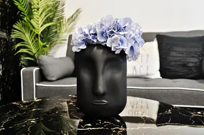 a black vase with blue flowers in it on a table at NEW Stylish 2BR Suite With Sofa Bed, 7 Mins to Niagara Falls and Sleeps 6 in Niagara Falls