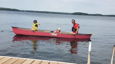 three people in a red boat on the water at The Clover - 91 Butternut in Cherry Valley