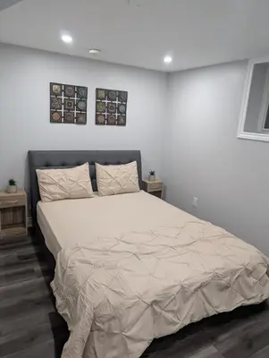a bed in a bedroom with two pictures on the wall at 2 Bedroom basement Apartment in Cambridge