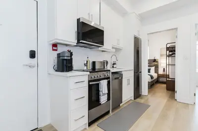 a kitchen with white cabinets and a stove top oven at The McCaul by Casa Hotels - Modern Group Suite in Toronto