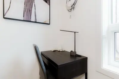 a black desk with a lamp on it next to a window at The McCaul by Casa Hotels - Modern Group Suite in Toronto