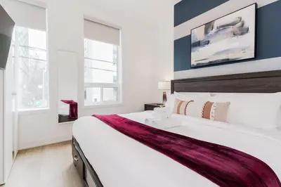 a bedroom with a large white bed with a sink at The McCaul by Casa Hotels - Modern Group Suite in Toronto