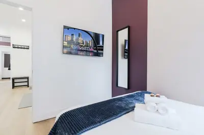 a bedroom with a bed with a tv on the wall at The McCaul by Casa Hotels - Modern Group Suite in Toronto