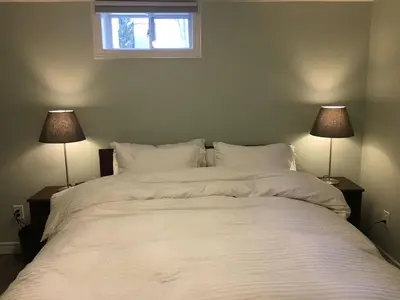 a bedroom with a large white bed with two lamps at Upscale 2-Bedroom Basement Apartment in London