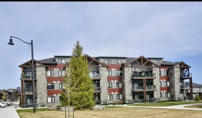 an apartment building with a tree in front of it at 3 Bdrm Blue Mountain Condo in Collingwood