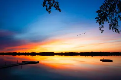 a sunset over a lake with boats on it at The Meadowlark - 115 Butternut in Cherry Valley