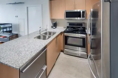 a kitchen with a stainless steel refrigerator and a sink at 3BR Urban Gem with Scenic Balcony Views in Toronto