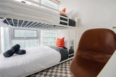a bedroom with a bunk bed and a chair at 3BR Urban Gem with Scenic Balcony Views in Toronto