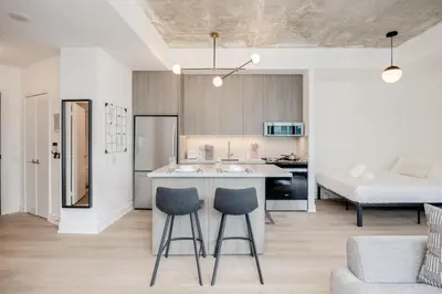 a kitchen and living room with a counter and two stools at Studio Gem in the lovely Waterfront Communities in Toronto
