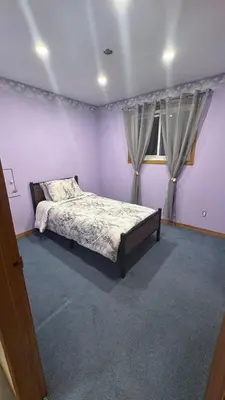 a bedroom with a bed with purple walls and a window at Welcome to our cozy private Home in Pickering