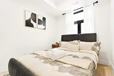a bedroom with a bed with white walls and a window at Cozy 2BR Suite with Parking & Close to Niagara Falls and Sleeps 6 Guests in Niagara Falls
