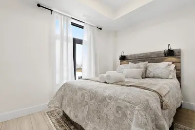 a white bedroom with a large bed and a window at Cozy 2BR Suite with Parking & Close to Niagara Falls and Sleeps 6 Guests in Niagara Falls