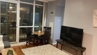 a living room with a table and chairs and a television at 1 BD and Den at Scotiabank Arena in Toronto