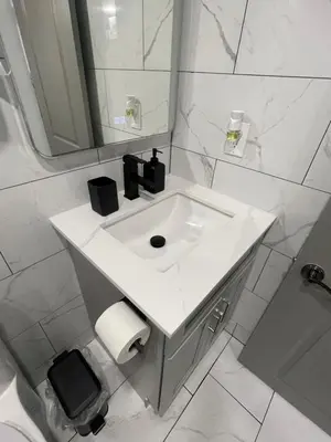 a white bathroom with a sink and a mirror at Luxury Basement-Private Bdr & Bathroom with free parking In Toronto in Toronto