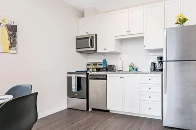 a kitchen with white cabinets and a stainless steel refrigerator at DT High Rise Condo w Private Patio and View in Kitchener