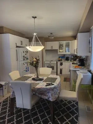 a kitchen with a table with chairs and a vase of flowers on it at 308 Delancey in Hamilton