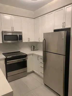 a kitchen with white cabinets and a stainless steel refrigerator at Cityscape in Mississauga