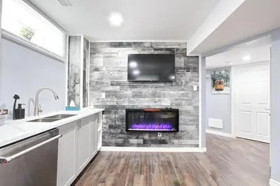 a kitchen with a fireplace with a tv on a brick wall at Deluxe Apartment in Caledon