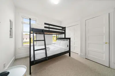 a black bunk bed in a white room with a window at The Finch - 59 Butternut in Cherry Valley