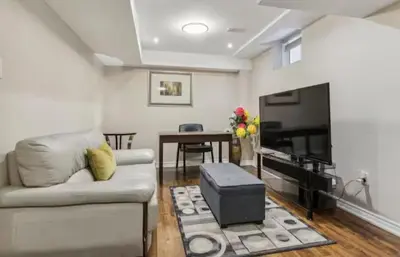 a living room with a couch and a flat screen tv at Comfortable & Cozy 2BR Hideaway Basement Appartment in Brampton