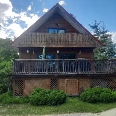 a large wooden house with a large deck at Cottage by the beach in Wasaga Beach