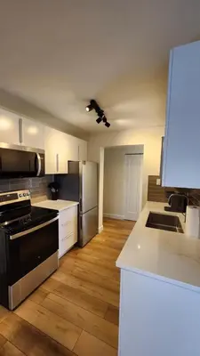 a kitchen with white cabinets and a black stove at ENTIRE 2 BEDROOM APARTMENT by UW RESEARCH PARK - PS5 in Waterloo