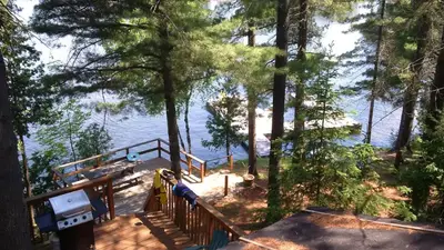 a deck with trees and a view of the water at Private Lakefront Family Cottage with Tennis Court in Kinmount