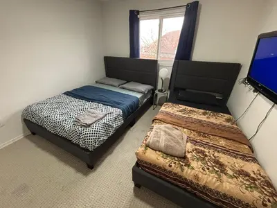 a bedroom with two beds and a flat screen tv at HOMESTAY NEXT TO SQUARE ONE MALL- 5 Mins Airport-24 HRS CHECKIN-MAJOR COST CUT in Mississauga