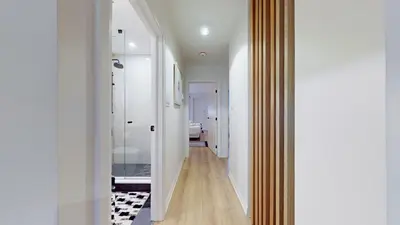 a hallway with white walls and wood floors and a mirror at Casa Hotel Elegant 2BR Suite in Leslieville in Toronto