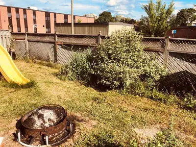an old rusted barrel sitting in the grass next to a playground at Earth Tone Suites in Pickering