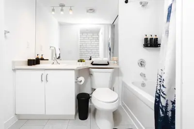 a white bathroom with a toilet and a sink and a tub at Downtown Cozy 1BR Condo- Steps from Lake & King street in Toronto