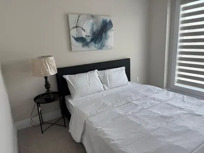 a bedroom with a white bed and a lamp at Cozy 3 Bedroom Townhome Hyde Park Mall & Western University in London