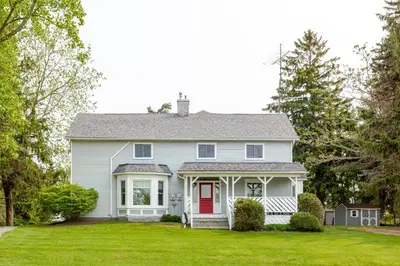 a white house with a red door on a yard at Westlake Cottages - Highway House in Wellington