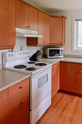 a white stove top oven in a kitchen with wooden cabinets at Westlake Cottages - Highway House in Wellington