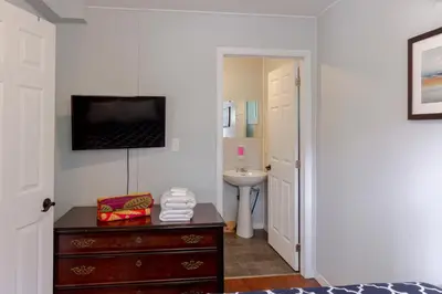 a bathroom with a bedroom with a sink and a dresser at Westlake Cherry Valley Cottage in Wellington