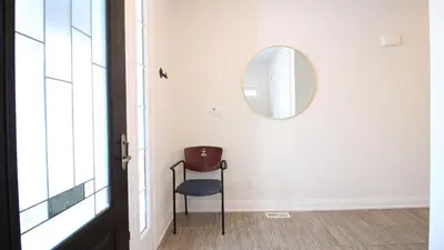 a hallway with a chair and a mirror at Beautiful House Near Grand River & Kiwanis Park in Kitchener