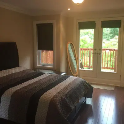 a bedroom with a bed and two windows and a balcony at Luxury Home - Upper Toronto Beaches in Toronto