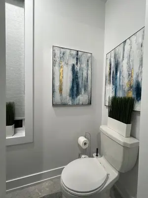 a bathroom with a toilet with two paintings on the wall at French Style Mansion In Prestigious Angus Glen Markham in Markham