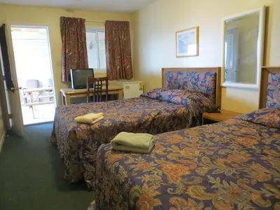 a hotel room with two beds and a desk at Villa Nova Motel in Wasaga Beach